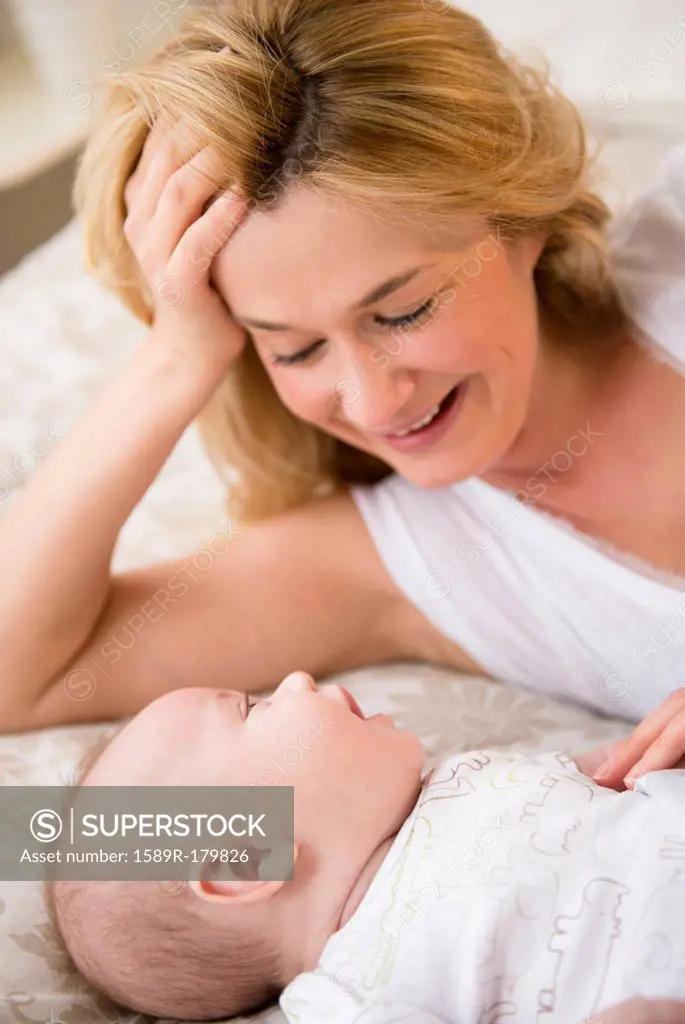Caucasian mother and baby laying on bed