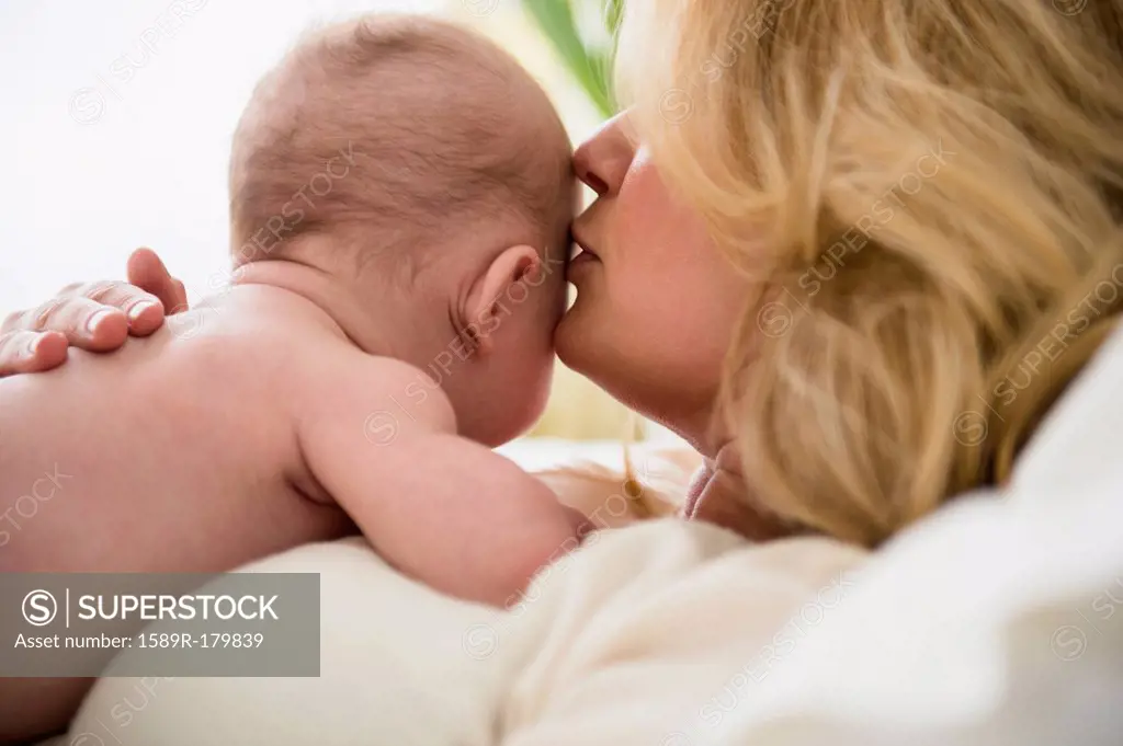 Caucasian mother kissing baby