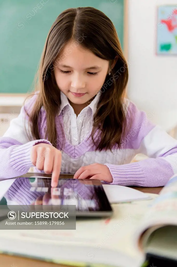 Mixed race girl using tablet computer in class