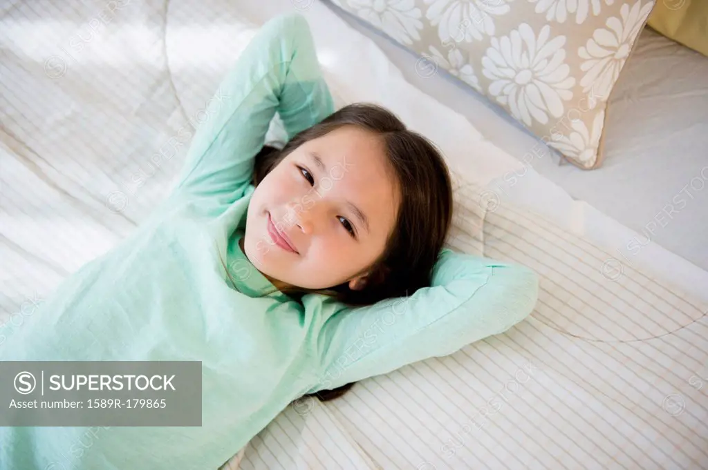 Mixed race girl smiling on bed