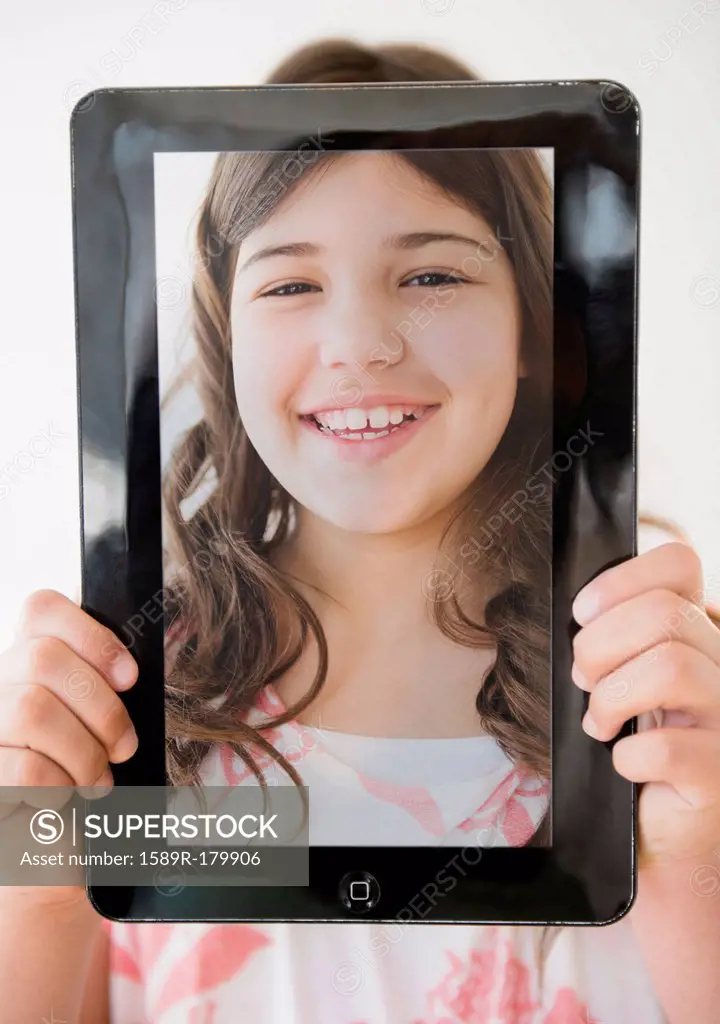 Hispanic girl holding tablet with picture of her face