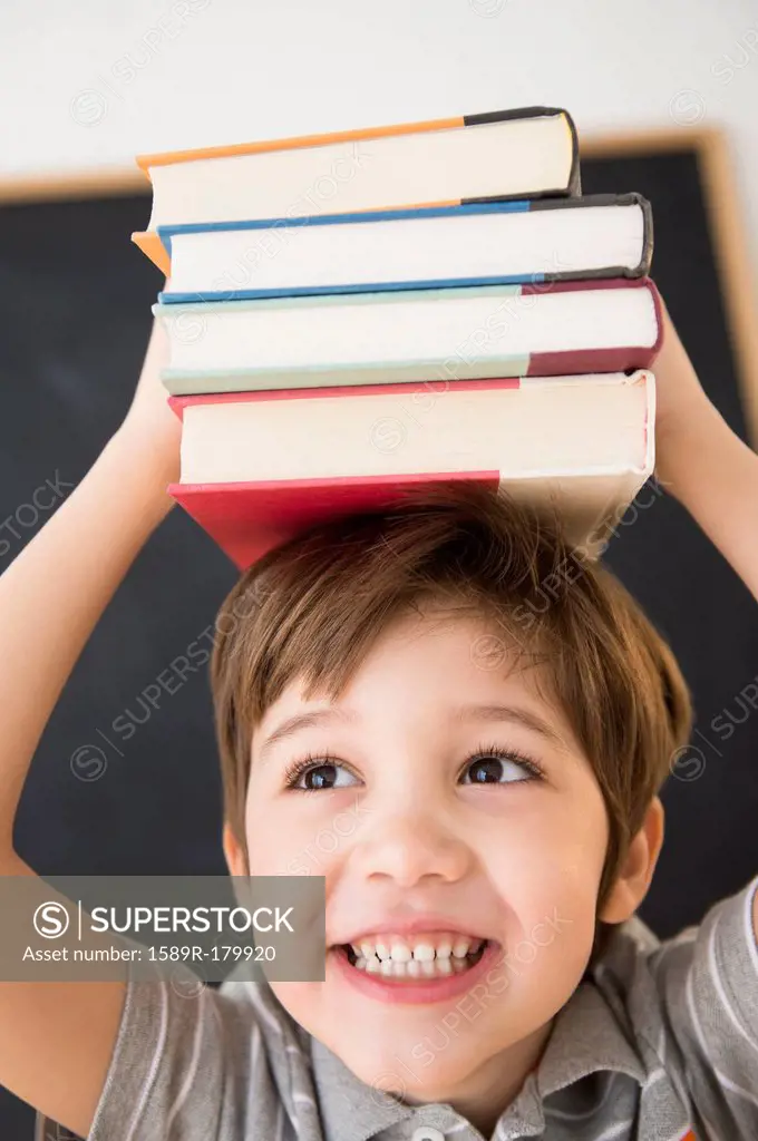 Hispanic boy balancing books on head