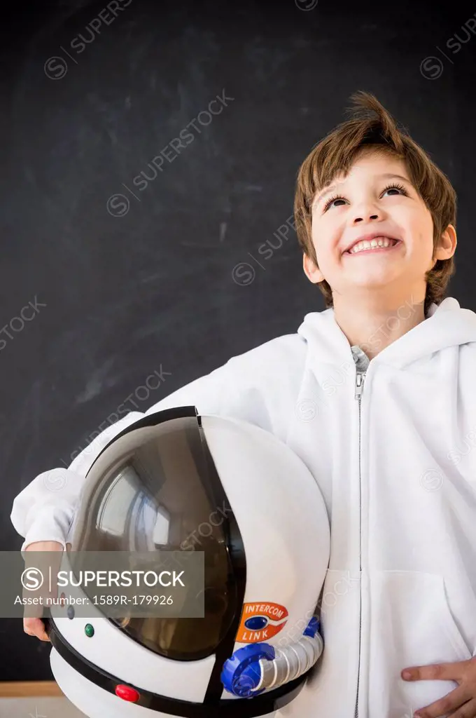 Hispanic boy holding space helmet in classroom