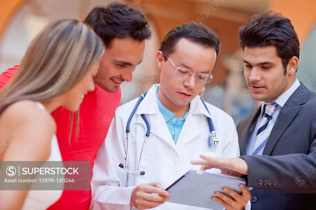 Hispanic people and doctor using tablet computer in gym