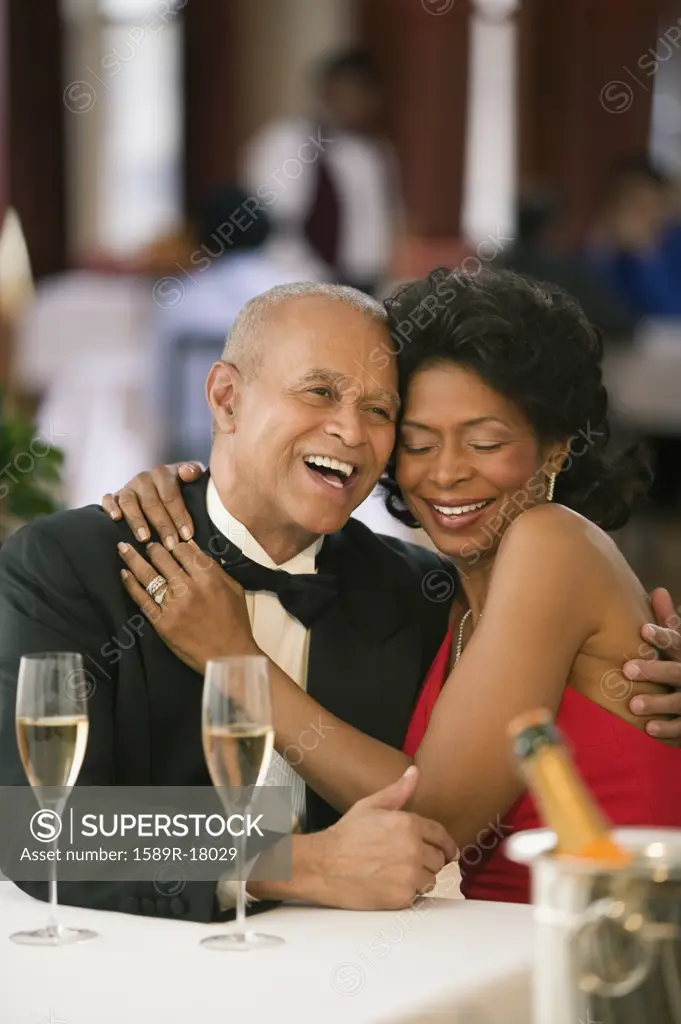 Couple hugging and laughing at dinner table