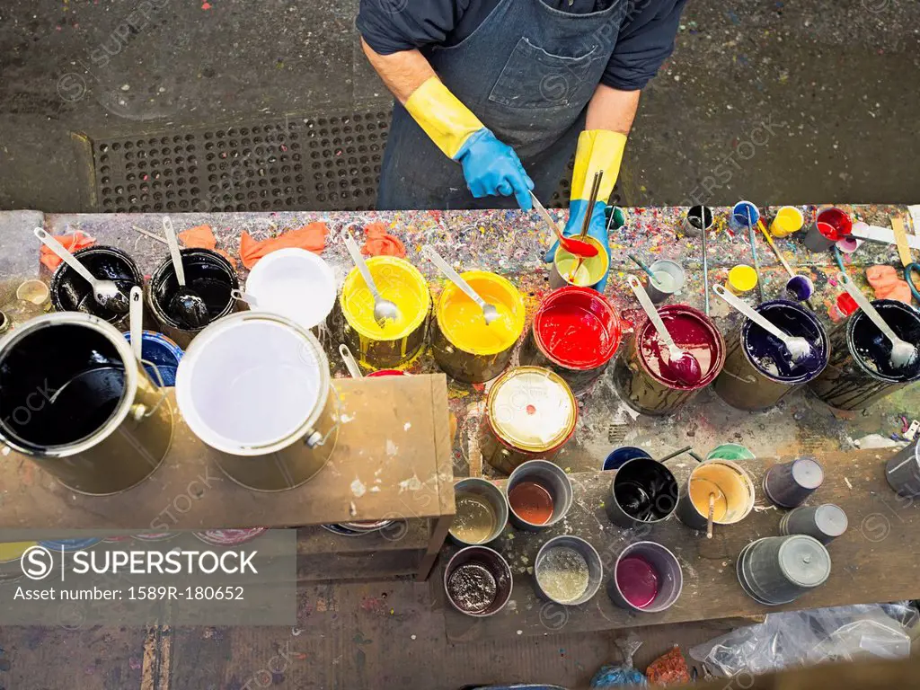 Hispanic worker mixing paint in workshop
