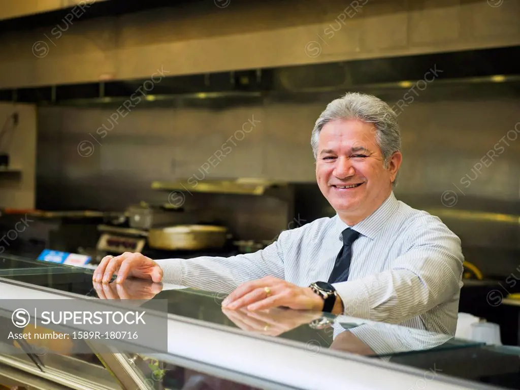 Hispanic businessman smiling in kitchen