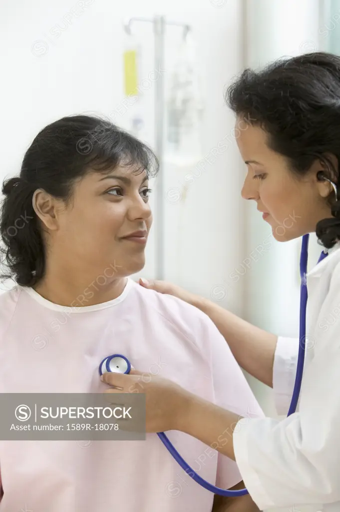 Doctor checking female patient with stethoscope