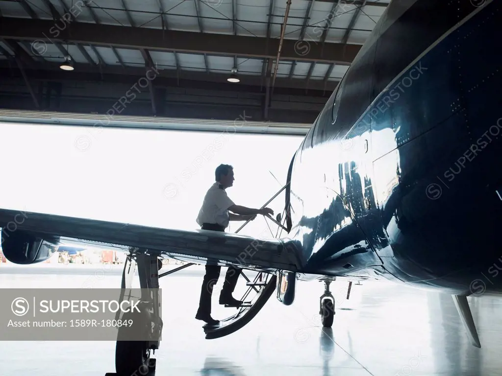 Caucasian pilot boarding airplane in hangar