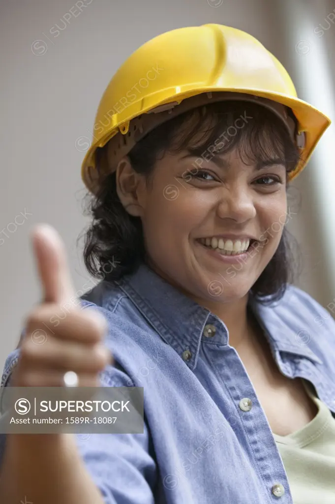 Woman construction worker in hard hat giving thumbs up
