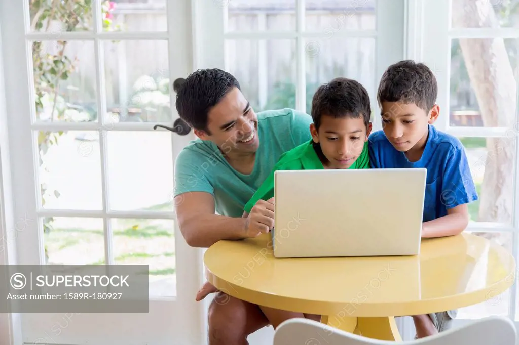 Hispanic father and sons using laptop