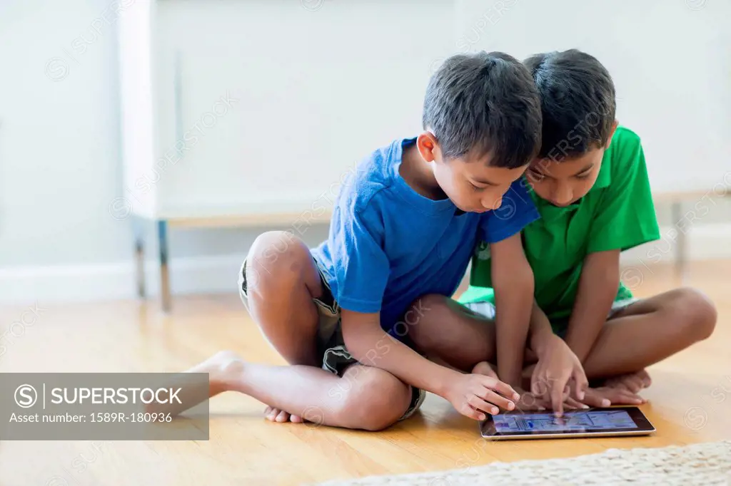 Boys using digital tablet on floor