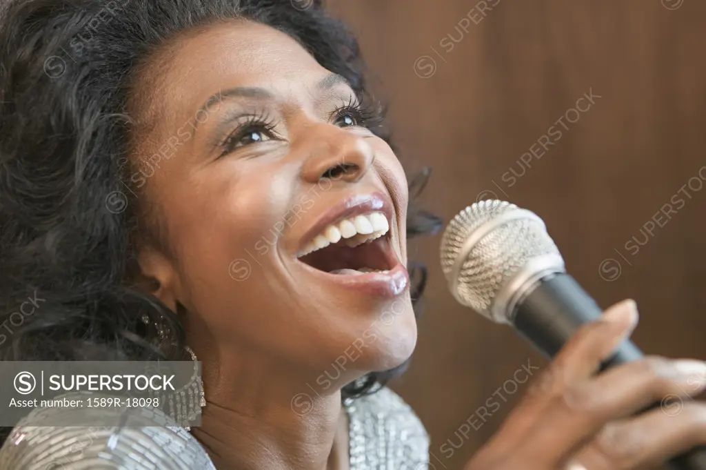 Close up of African American woman singing with microphone