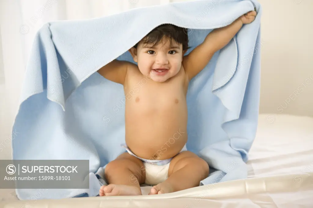 Portrait of toddler boy sitting in diaper with blanket