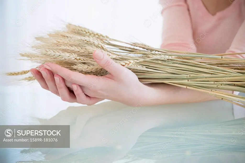 Caucasian woman holding stalks of wheat