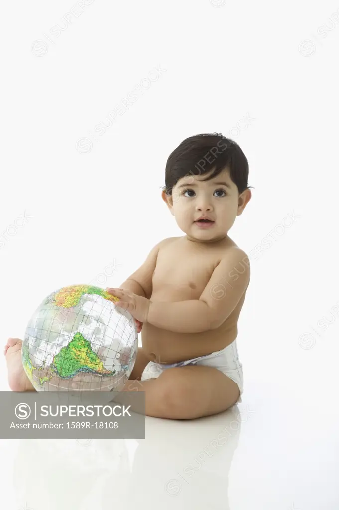 Toddler boy in diaper sitting with globe