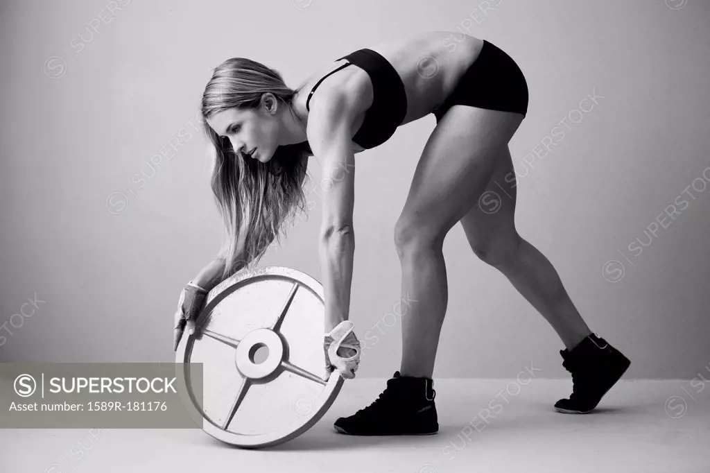 Caucasian woman lifting weight disc