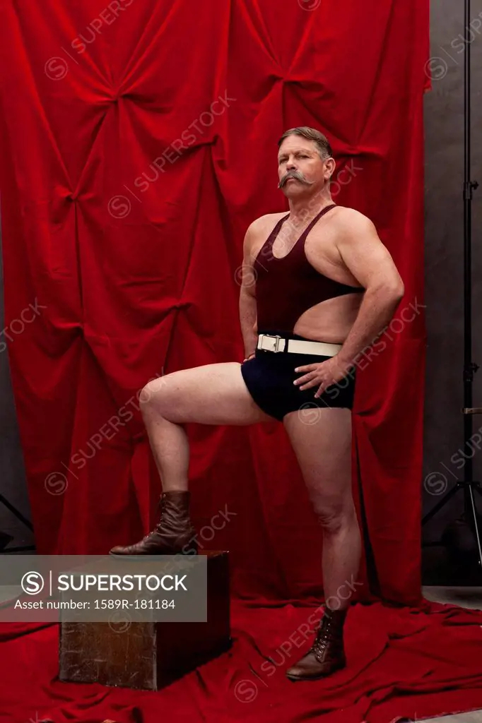Caucasian weight lifter posing by curtain