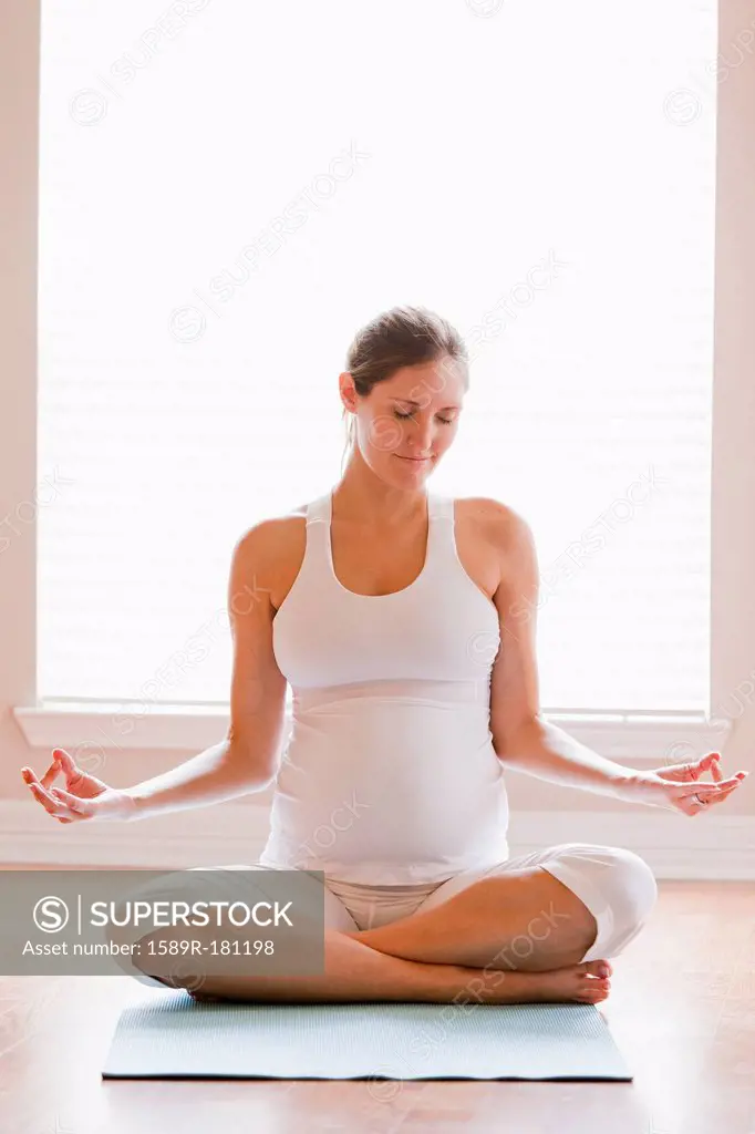 Pregnant woman meditating on yoga mat