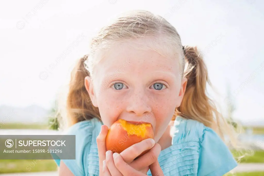Caucasian girl eating fruit outdoors