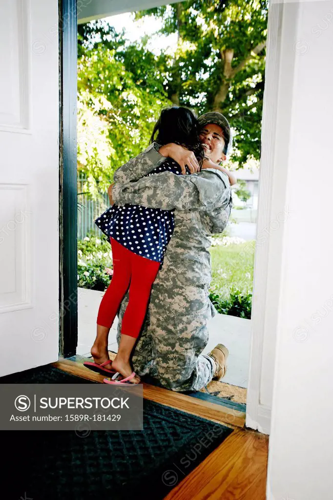 Mixed race soldier mother hugging daughter in front door