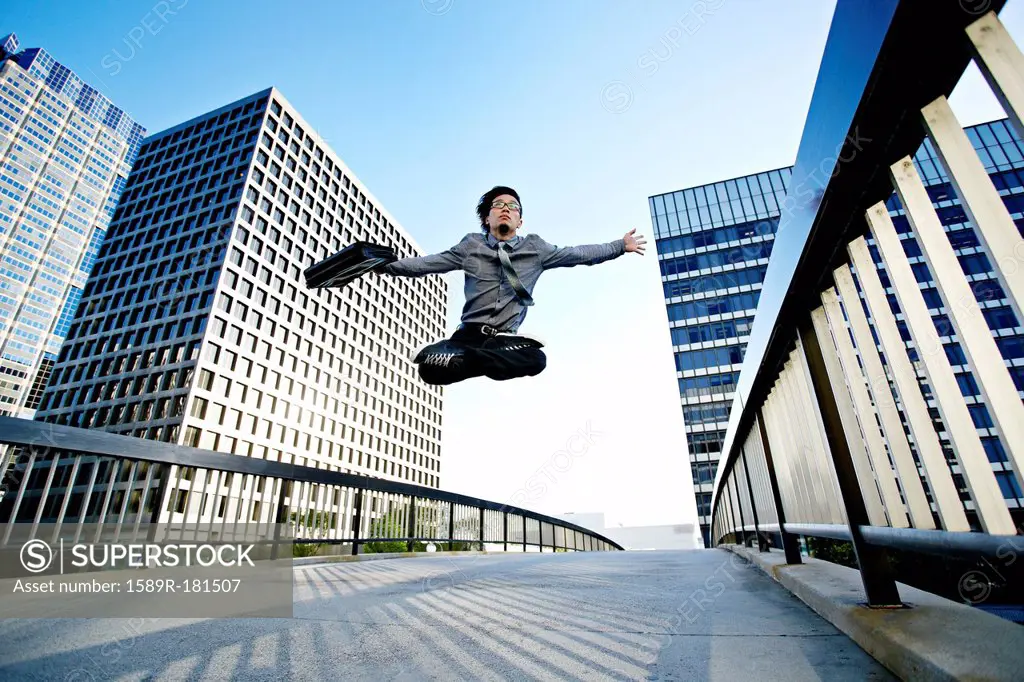 Asian businessman leaping on urban walkway