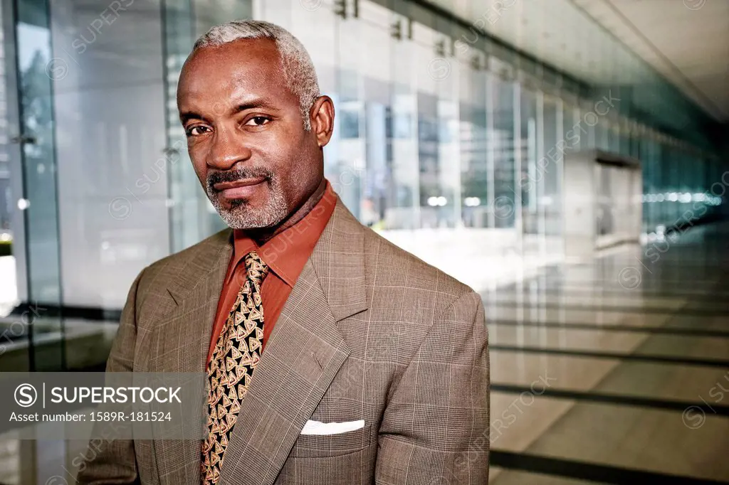 Black businessman smiling in office corridor