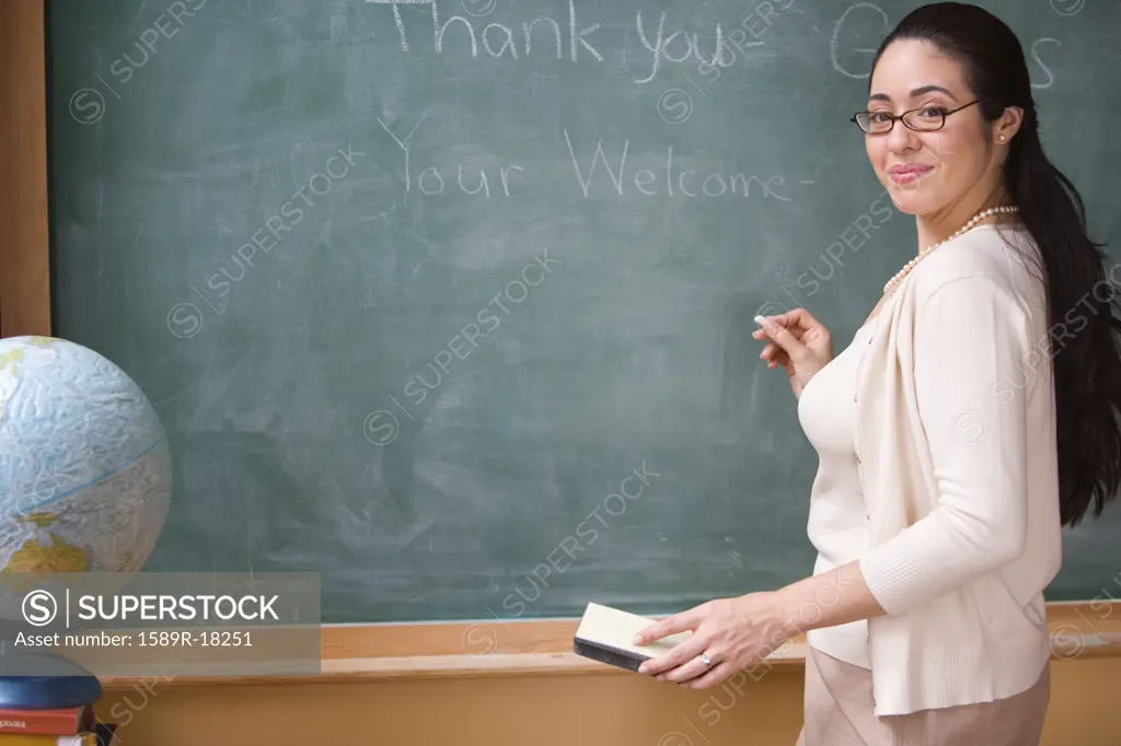 Portrait of female teacher writing on chalkboard