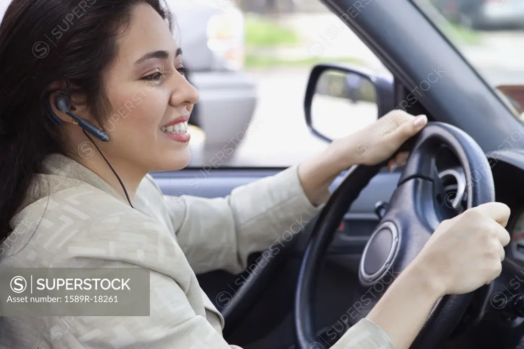 Profile of woman driving car with earpiece