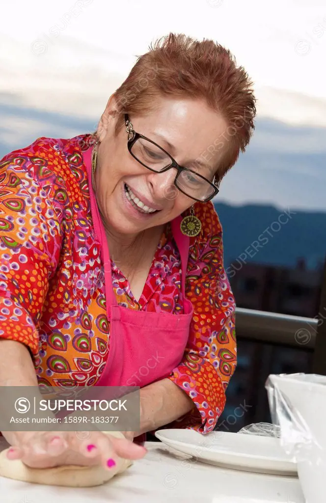 Older Hispanic woman kneading dough