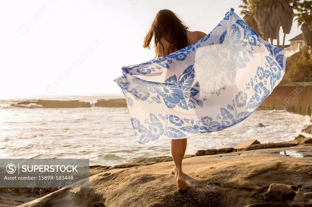 Japanese woman holding sarong on beach