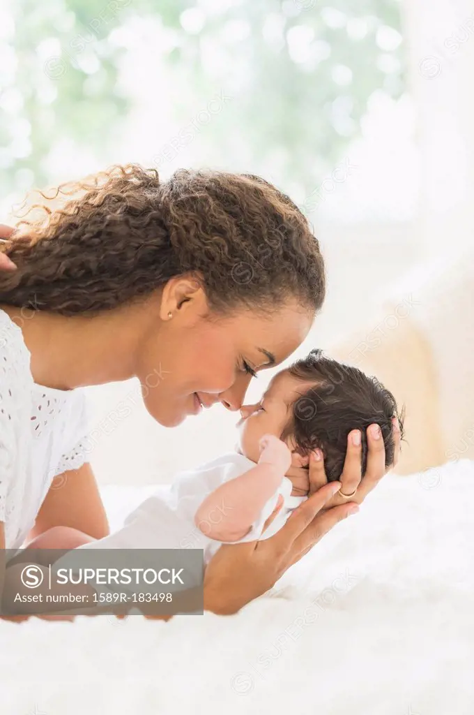Hispanic mother holding infant on bed