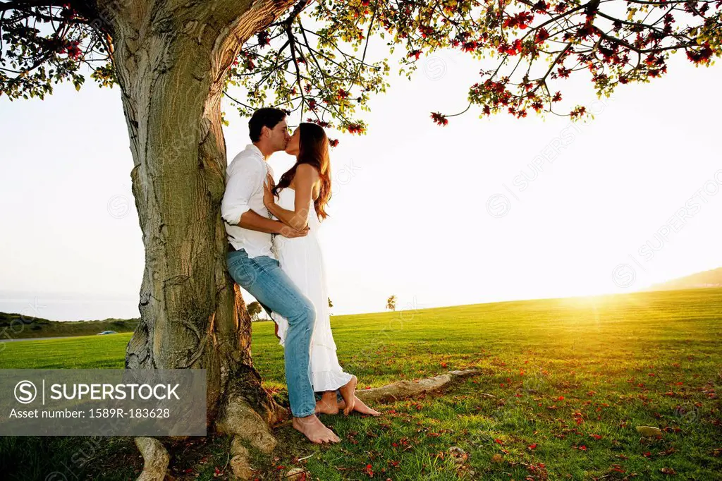 Couple kissing by tree in park