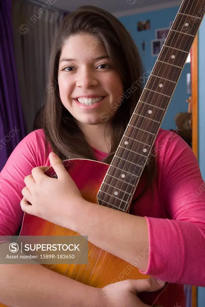 Hispanic girl hugging guitar