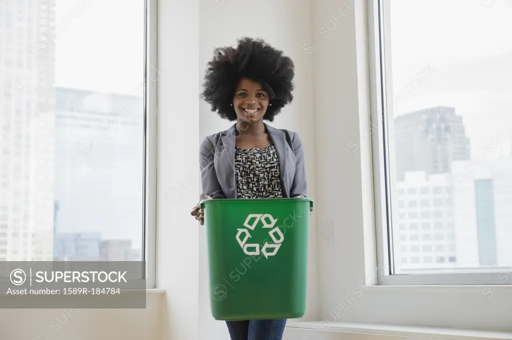 Mixed race businesswoman with recycling bin