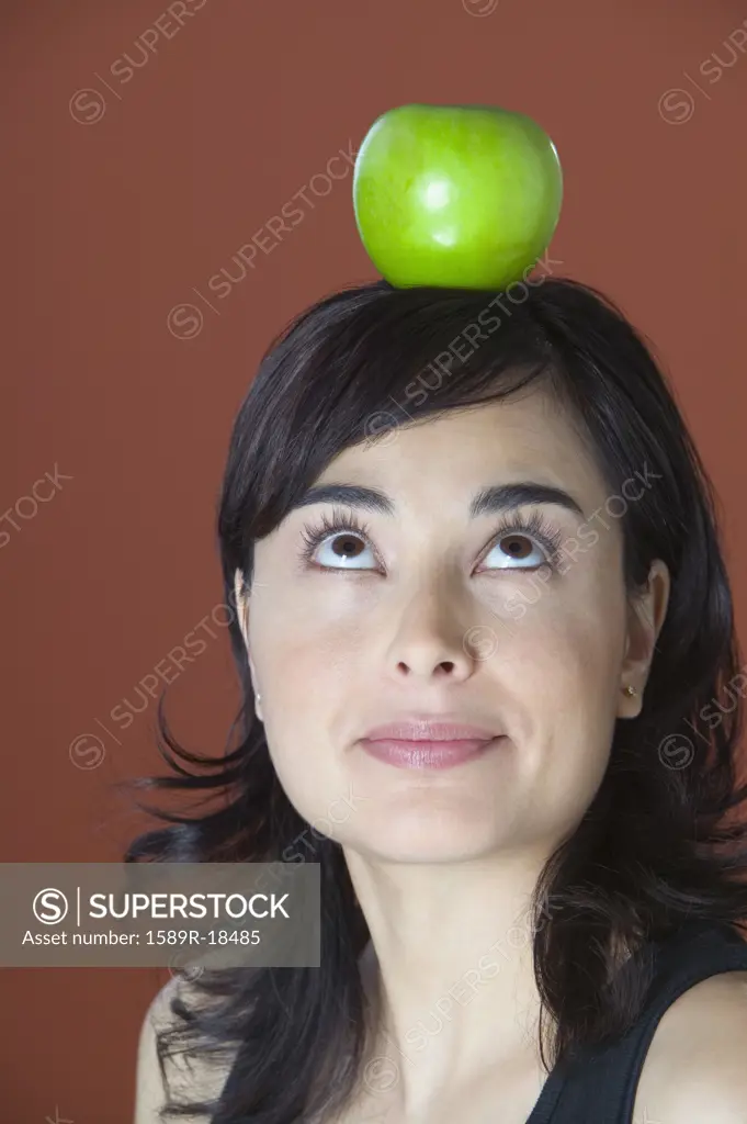 Woman posing with apple balanced on head