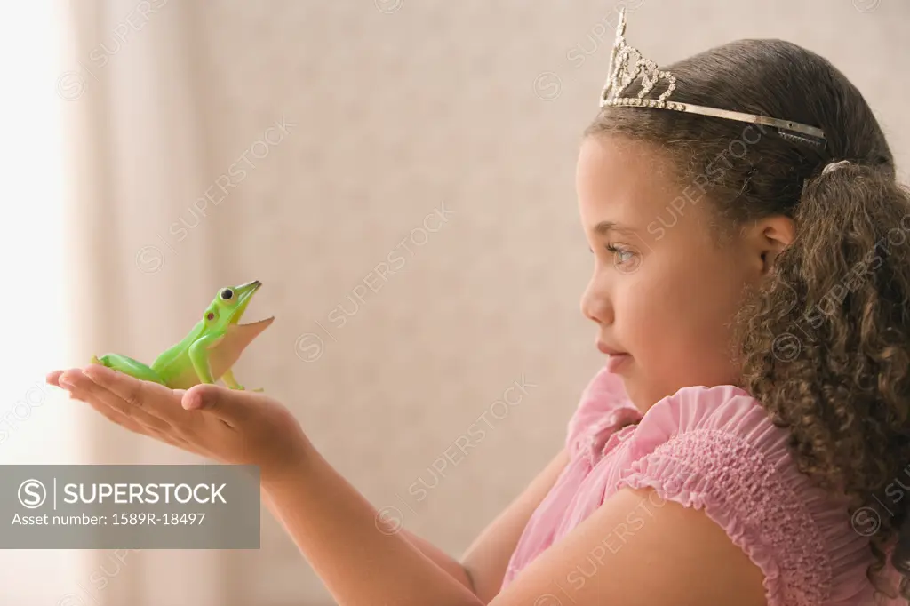 Profile of young girl wearing crown and holding frog