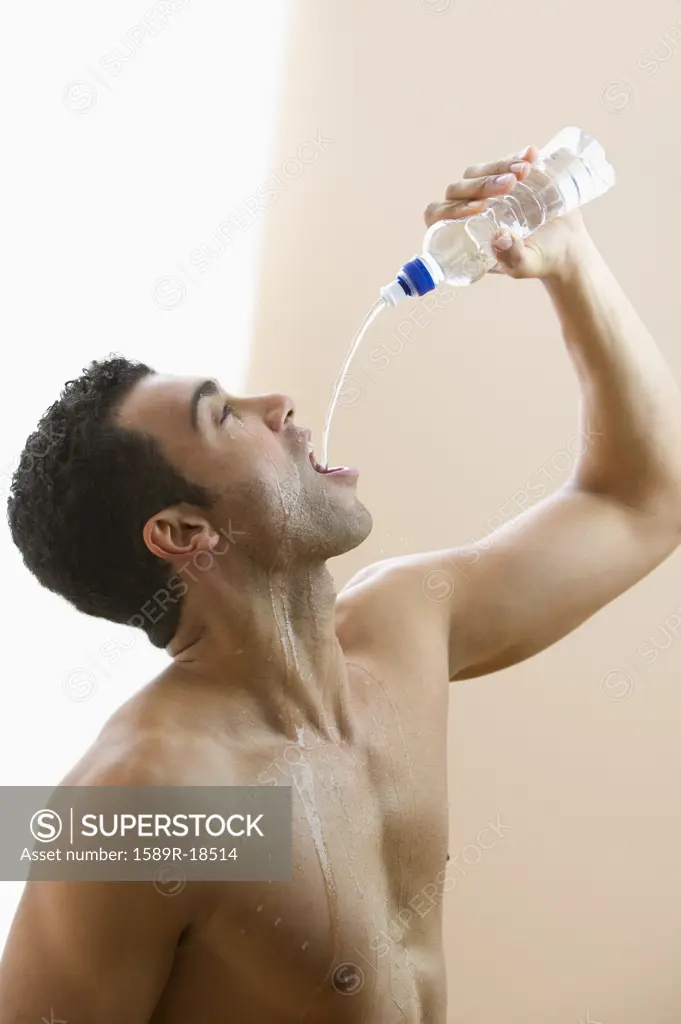 Profile of man pouring water in his mouth