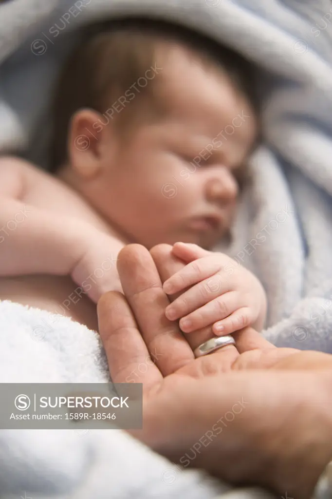 Sleeping baby holding fatherís hand