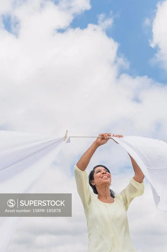 Black woman hanging sheets from clothesline