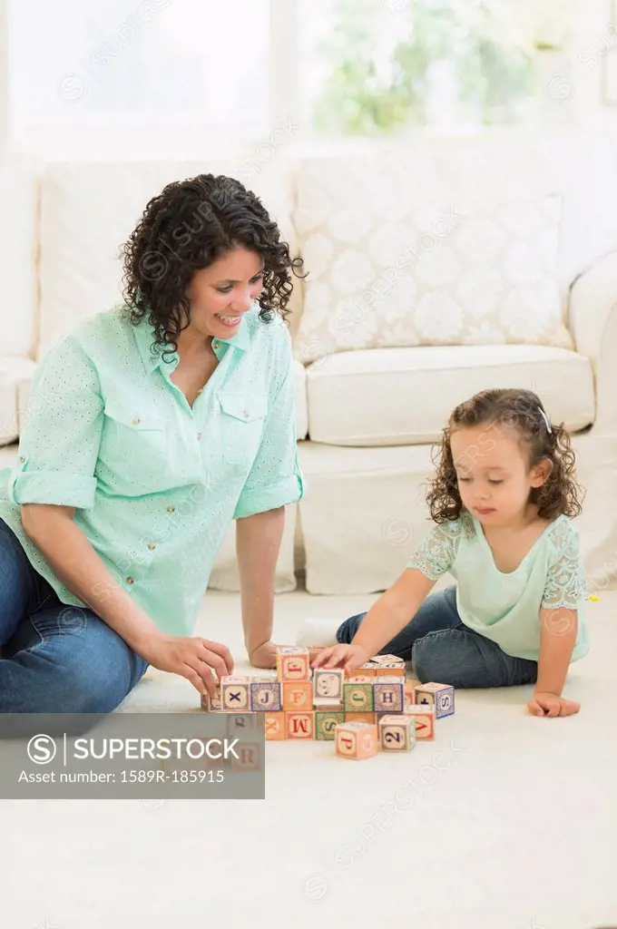 Mixed race mother and daughter playing with wooden blocks