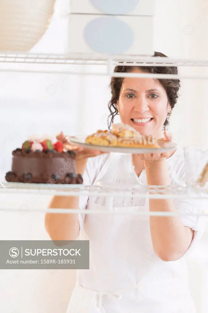 Hispanic baker holding fresh desserts