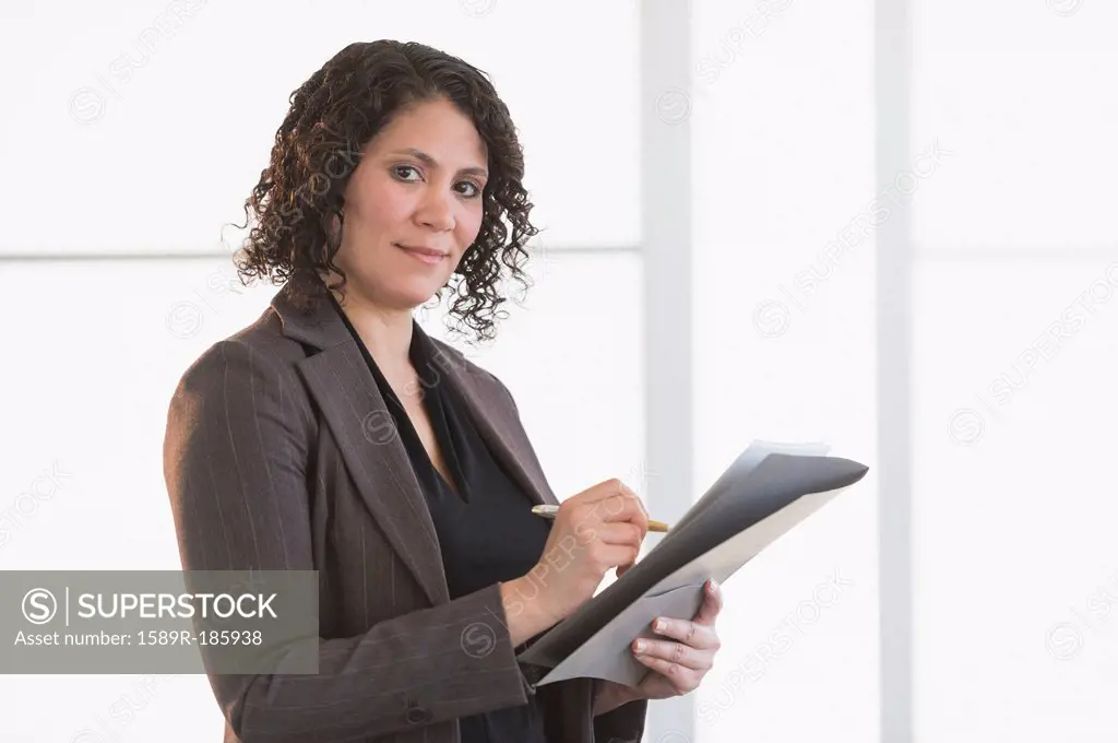 Hispanic businesswoman writing in office