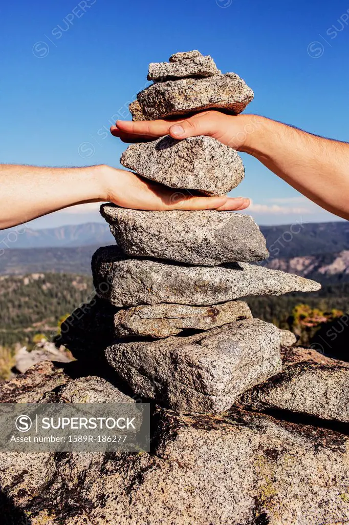 Caucasian couple stacking their hands in rocks