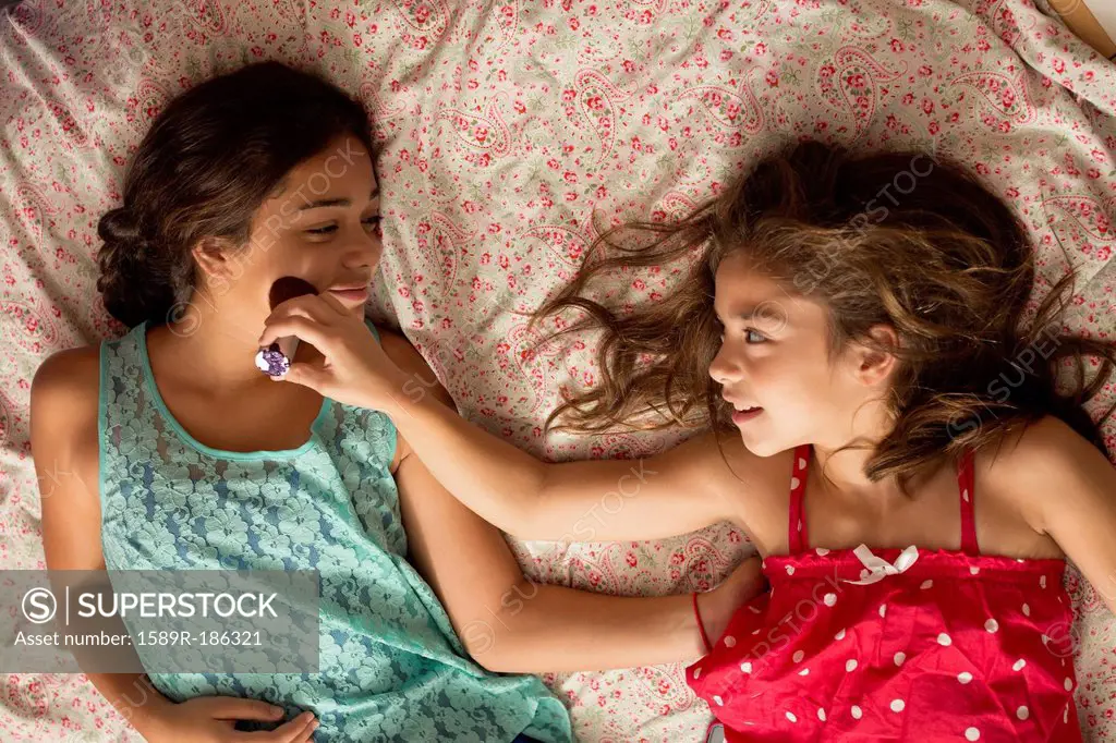 Mixed race sisters relaxing on bed