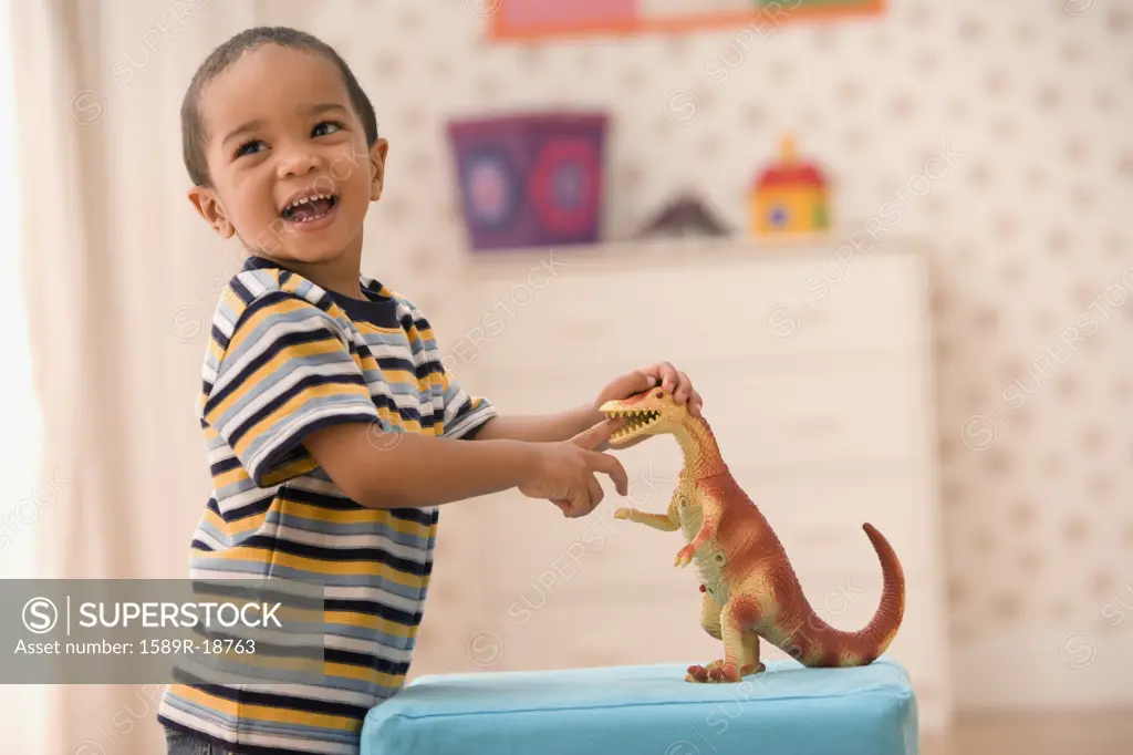 Young boy playing with toy dinosaur