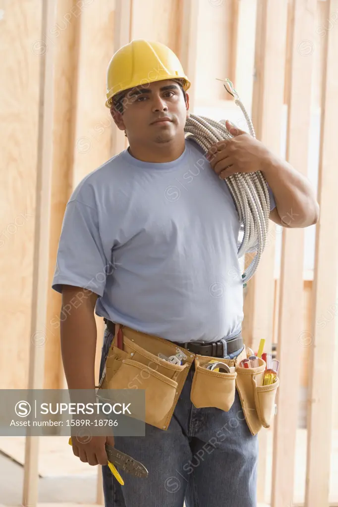 Construction worker carrying wiring on shoulder