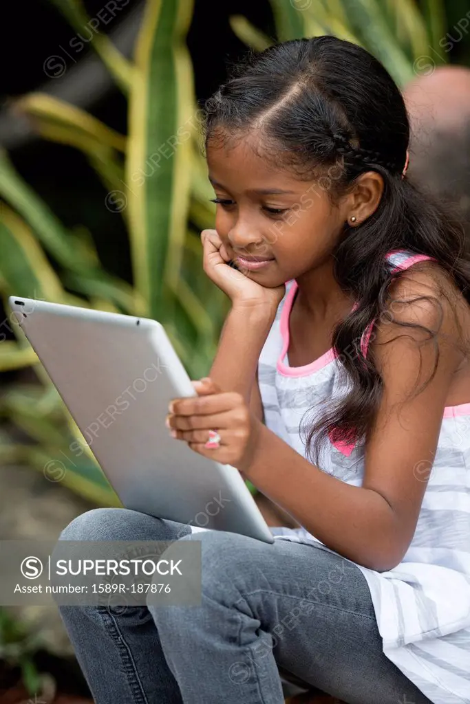 Mixed race girl using digital tablet outdoors