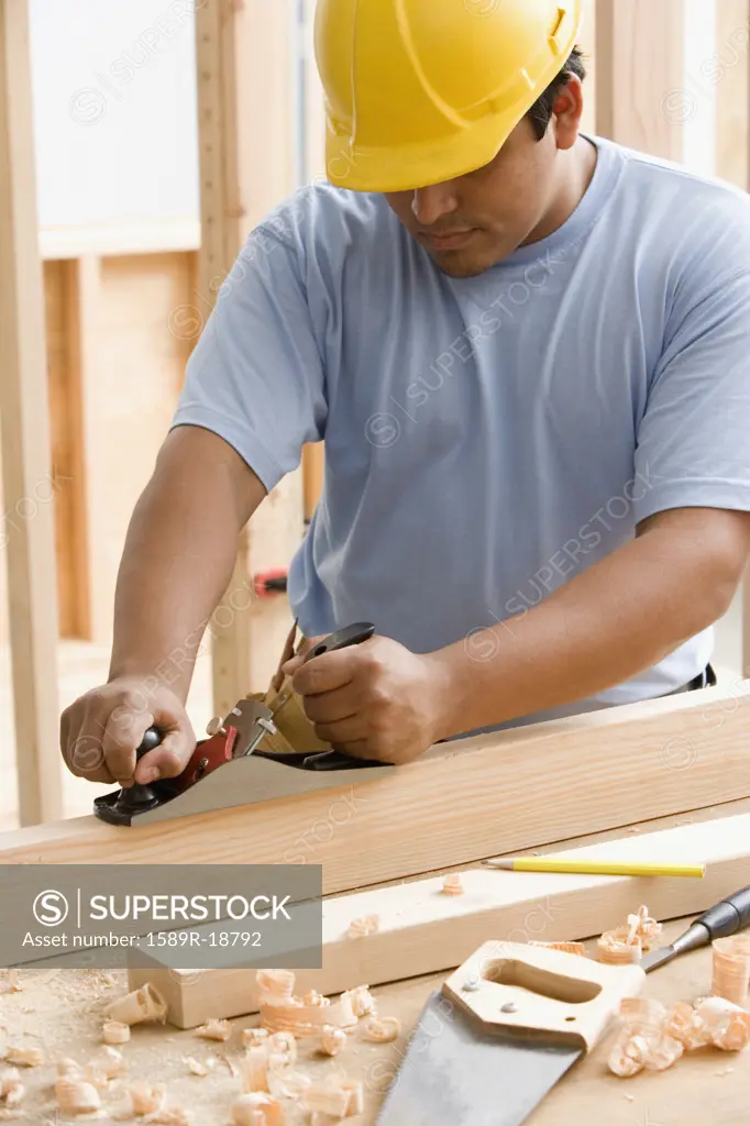 Construction worker planeing wood
