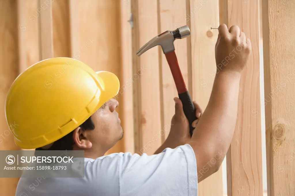 Construction worker nailing nail into wood